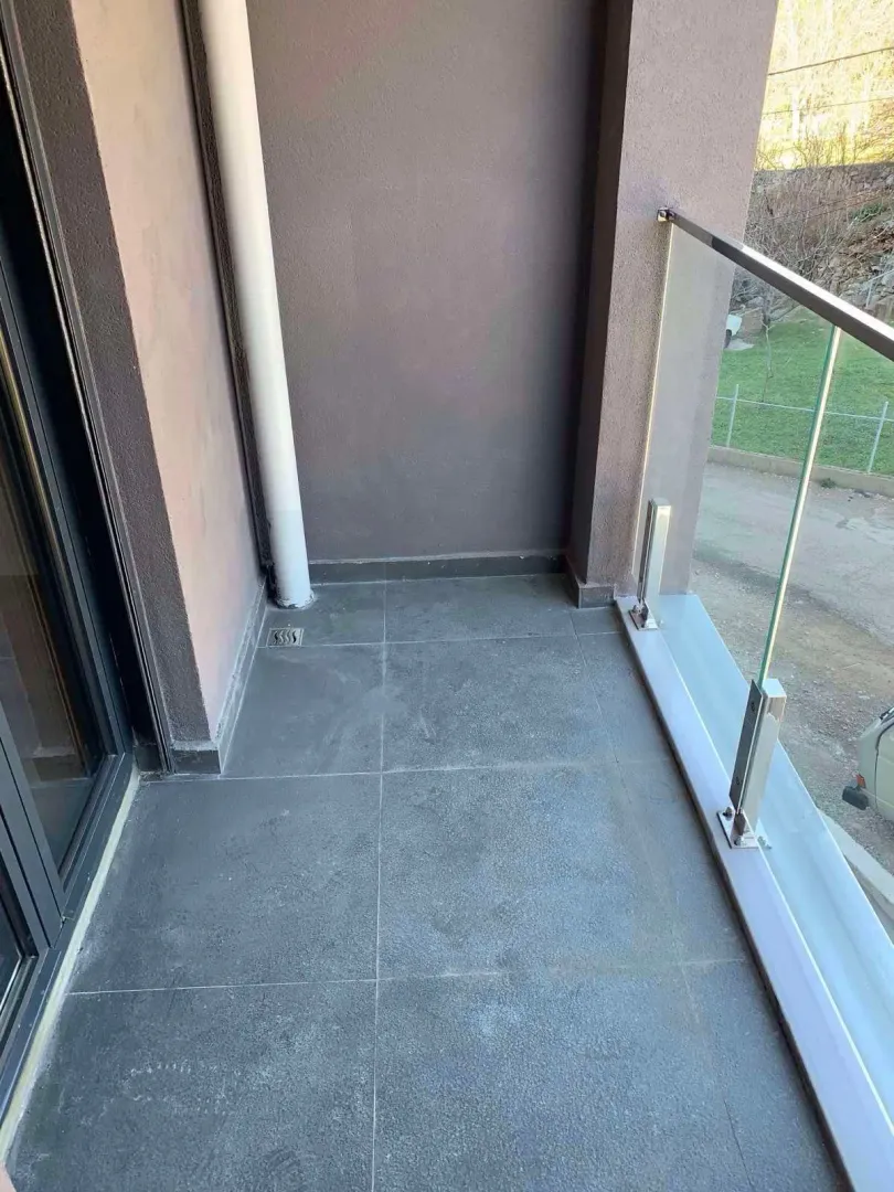 Unfurnished balcony with gray tiles and a glass railing.