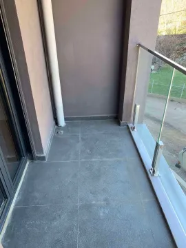Unfurnished balcony with gray tiles and a glass railing. - image 6