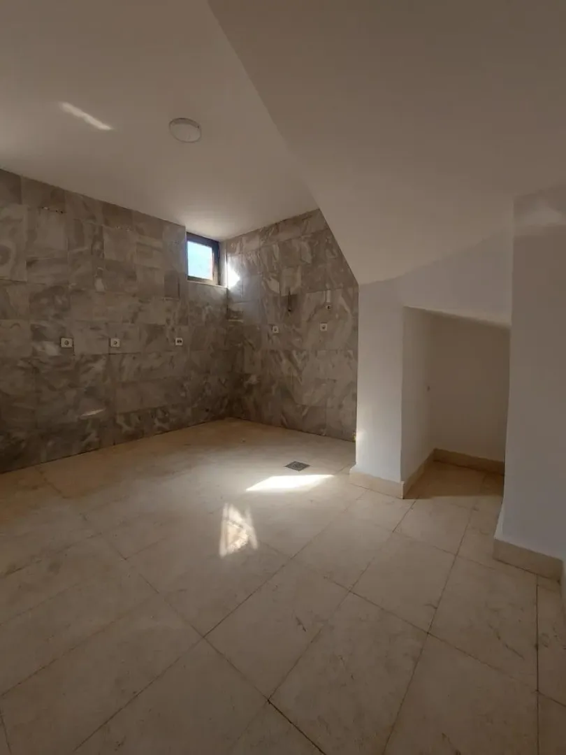 Empty bathroom with ceramic tiles and a small window.