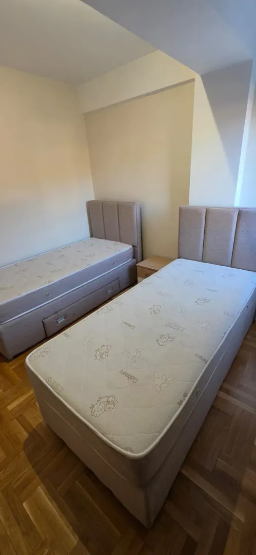 Spavaća soba sa dva singl kreveta i parketom na podu.