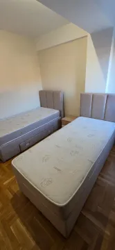 Spavaća soba sa dva singl kreveta i parketom na podu. - image 9