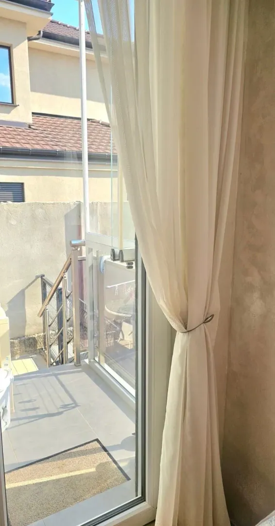 Balkonska vrata sa svijetlom zavjesom i pogledom na terasu.