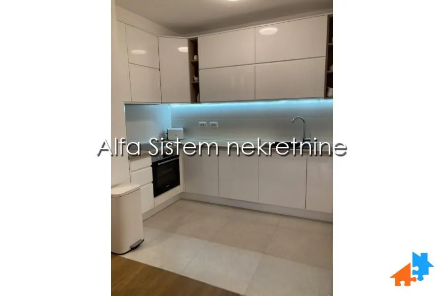 Modern white kitchen with built-in units and LED lighting.