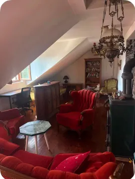 Potkrovlje uređeno kao dnevni boravak sa crvenim foteljama, drvenim podom i peći na drva. - image 9