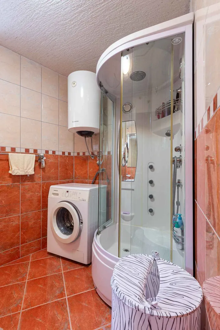 Bathroom with a shower cabin, water heater, and washing machine.