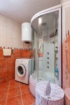 Bathroom with a shower cabin, water heater, and washing machine. - image 19