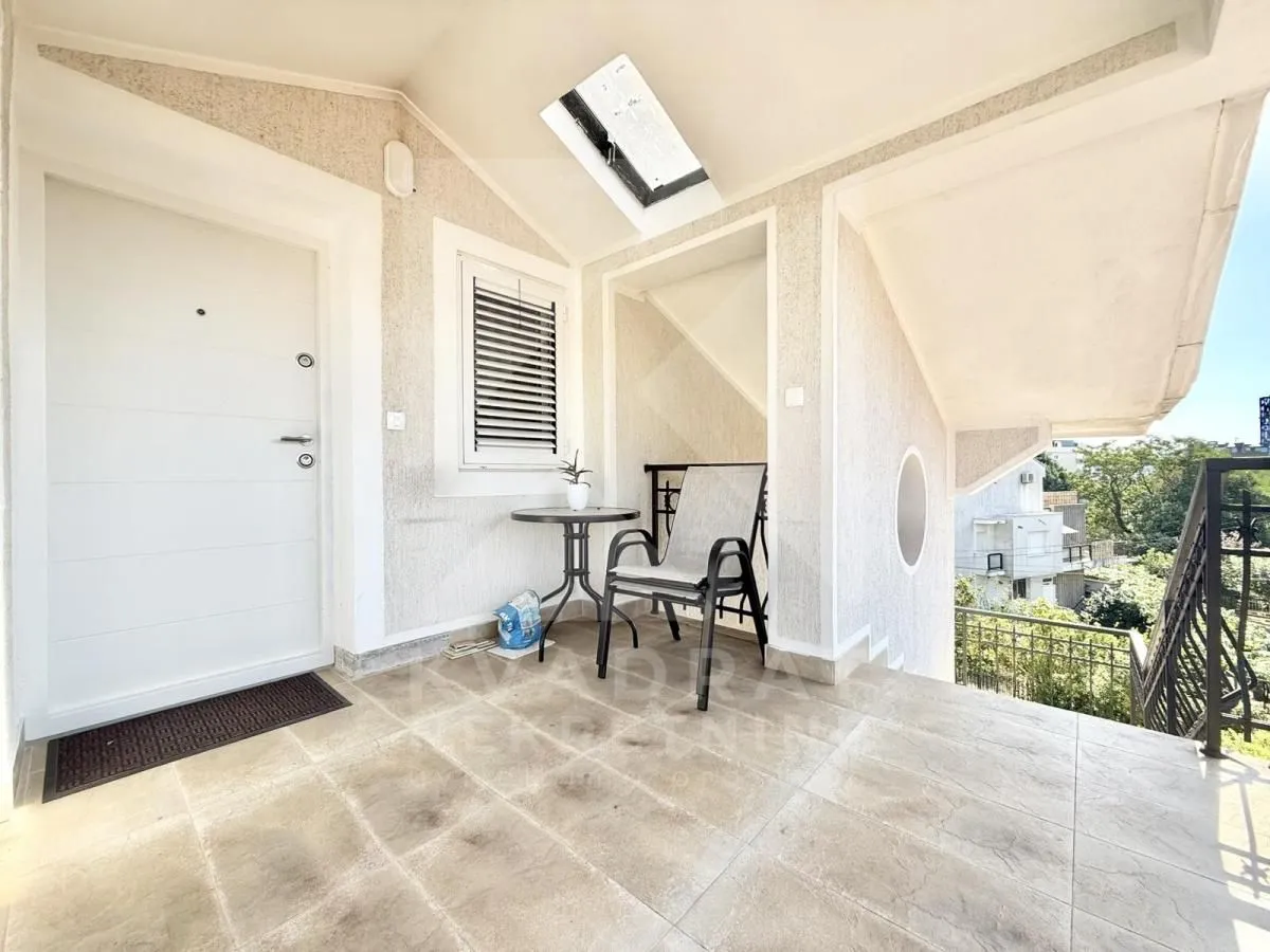 Covered terrace in front of the entrance with a table and chairs.
