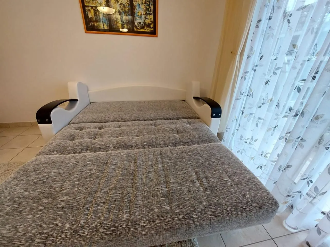 Dnevna soba sa razvučenim kaučem i prozorom sa zavjesama.