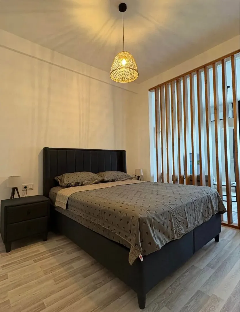 Bedroom with a double bed, nightstand, and wooden partition screen.