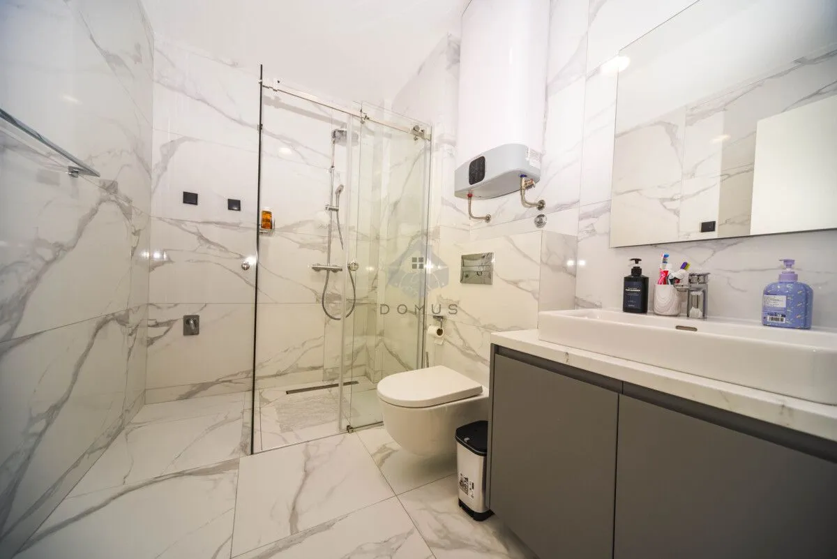 Moderne kupatilo sa tuš kabinom, umivaonikom i wc šoljom.