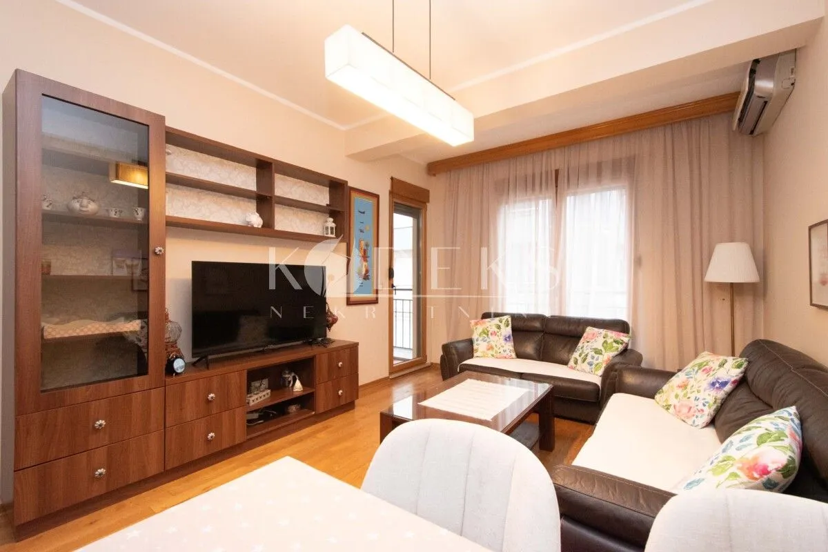 Living room with a sofa set, TV unit, and dining table.