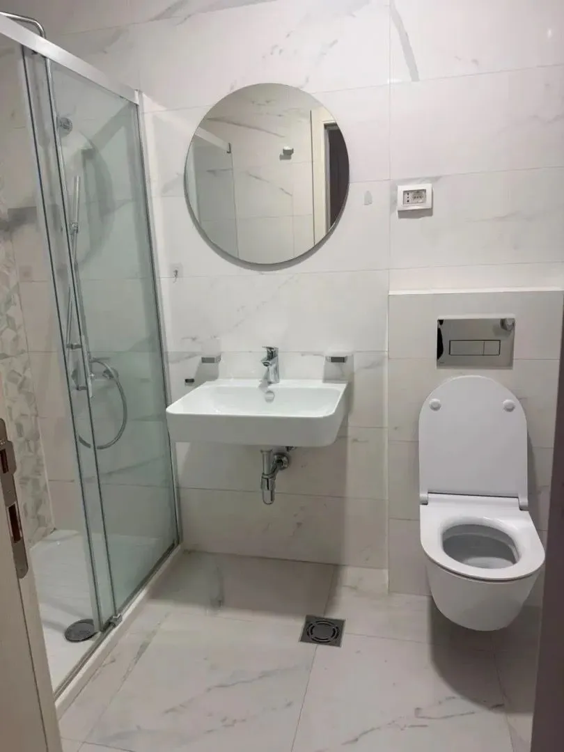 Modern bathroom equipped with a shower cabin, washbasin, and toilet.