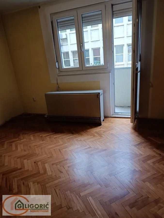 Empty room with parquet flooring, a window, and access to a balcony.