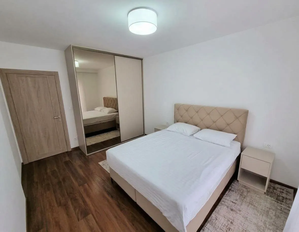 Furnished bedroom with a double bed and a built-in wardrobe with a mirror.