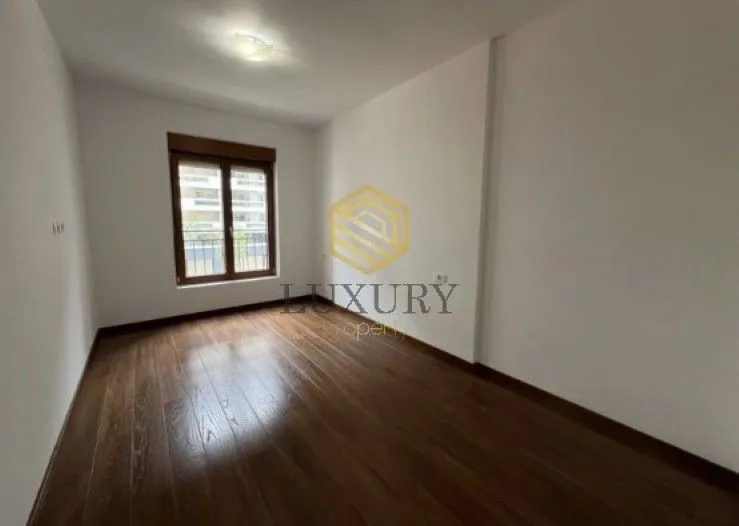 Empty room with wooden flooring and a window.