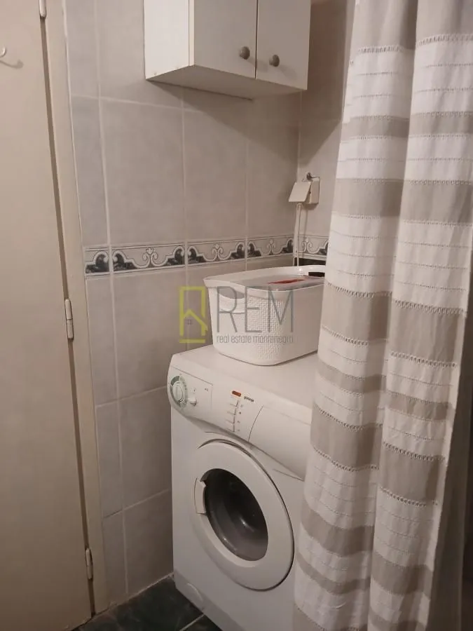 Small bathroom with a washing machine and shower curtain.