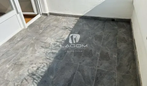Nenameštena terasa popločana sivim pločicama sa balkonskim vratima. - image 14