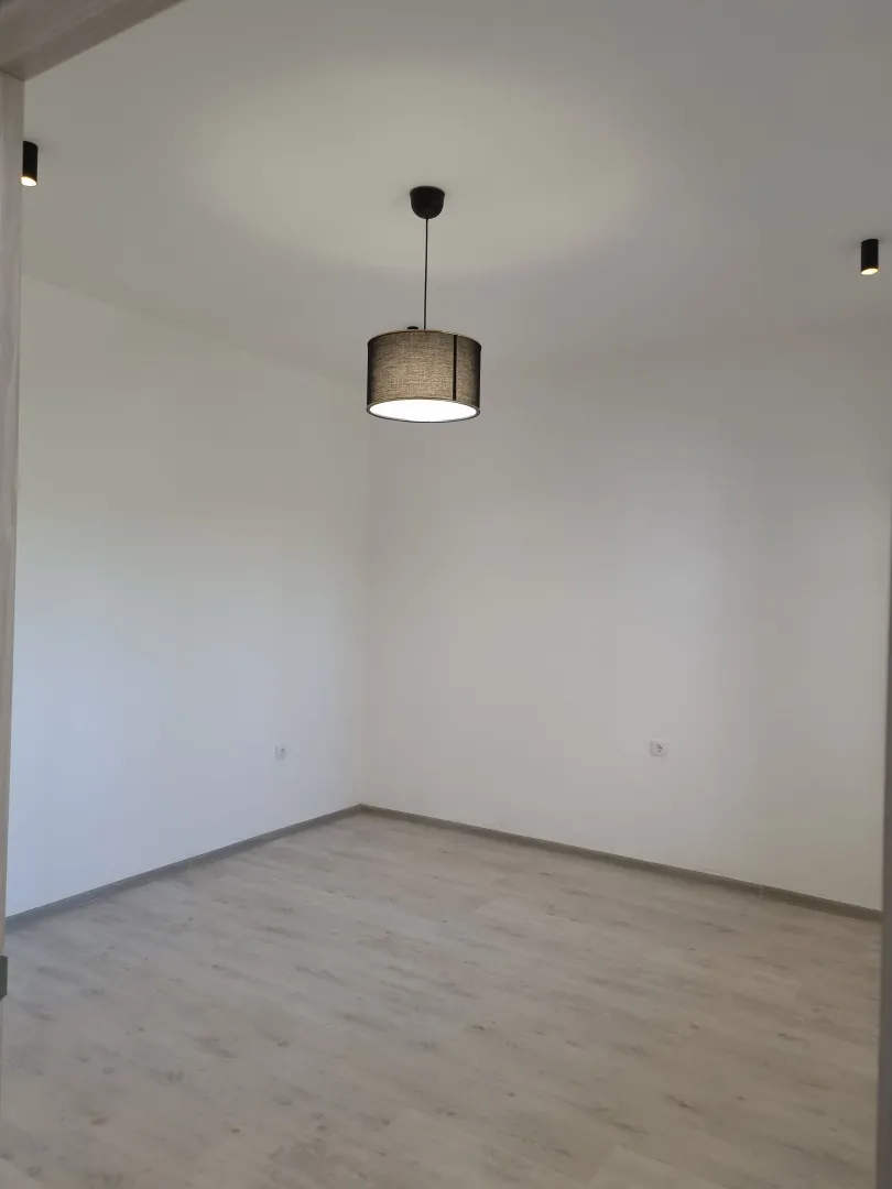 Empty room with white walls and light laminate flooring.