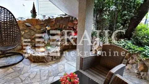 Landscaped courtyard with a stone wall, fountain, and seating set. - image 17