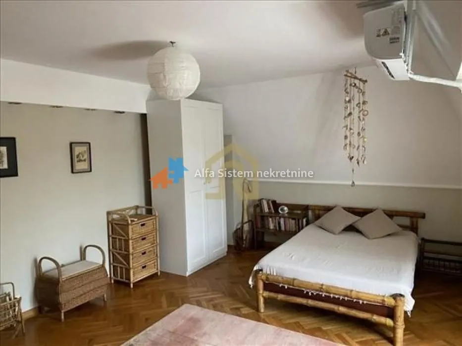 Furnished bedroom with a double bed, wardrobe, and wooden flooring.