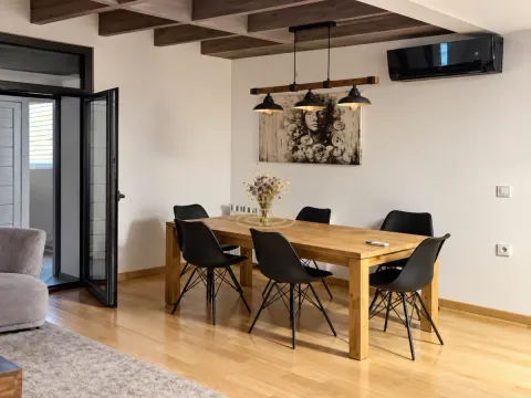 Dining area with a wooden table, black chairs and a chandelier. - image 4