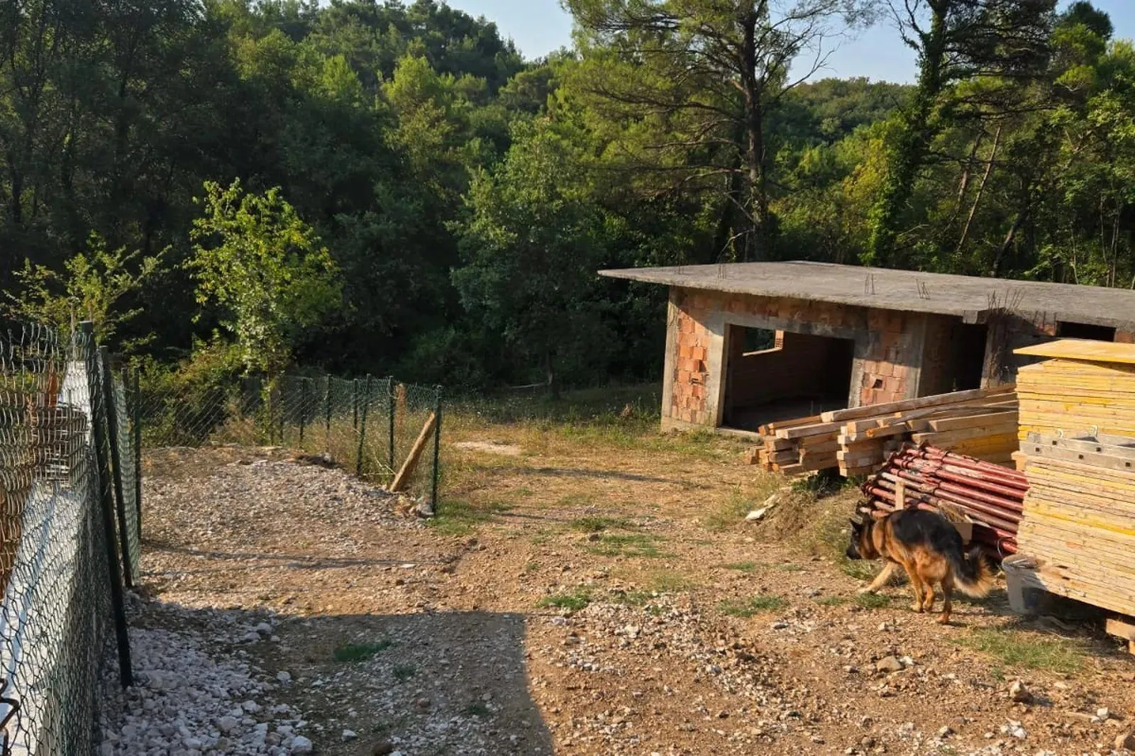 Pogled na dvorište i nedovršeni objekat u izgradnji.