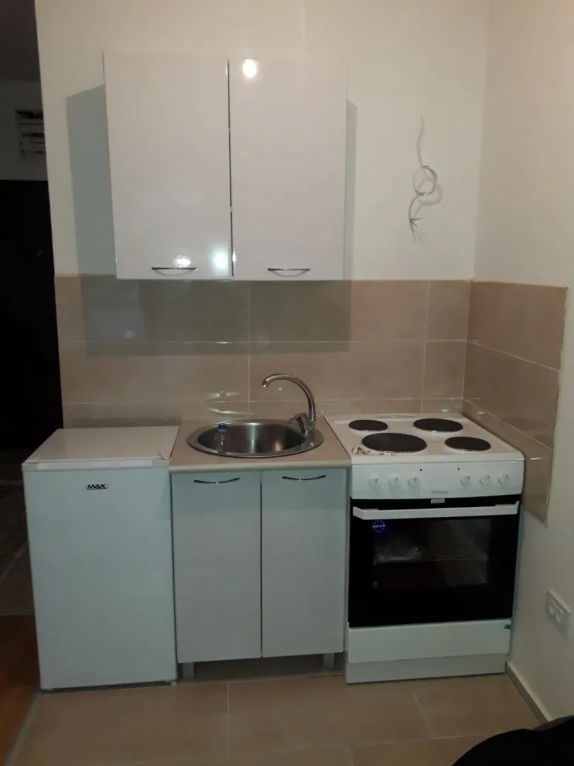 A small kitchen with white cabinets, a sink, and a stove.