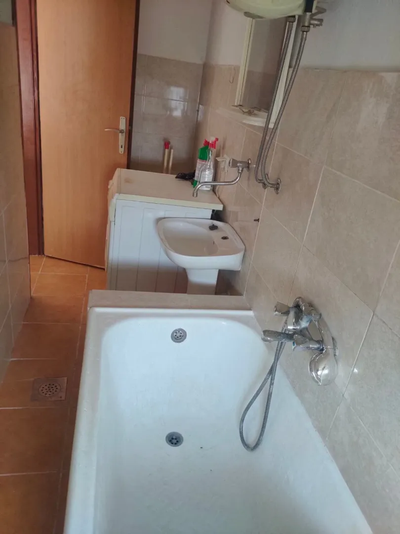Manje kupatilo sa kadom, umivaonikom i veš mašinom.