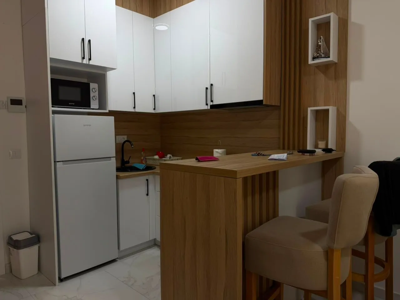 Modern kitchen with white cabinetry, built-in appliances, and a breakfast bar with chairs.