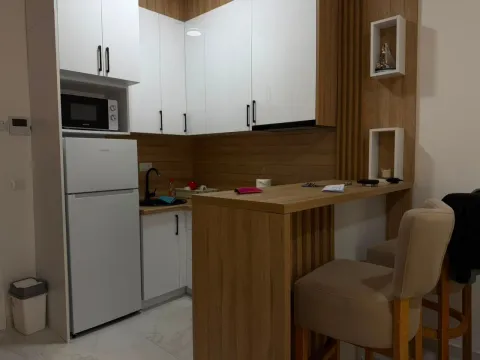 Modern kitchen with white cabinetry, built-in appliances, and a breakfast bar with chairs. - image 3