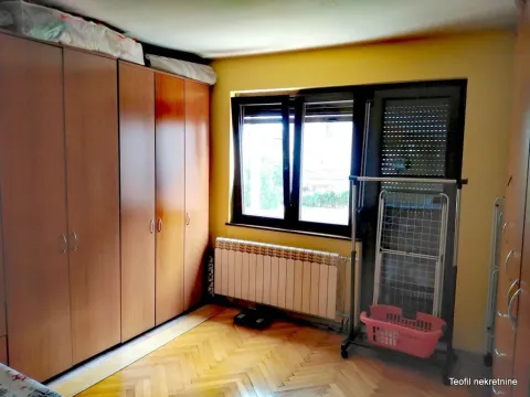 Spavaća soba sa velikim drvenim ormarima, prozorom i radijatorom. - image 11