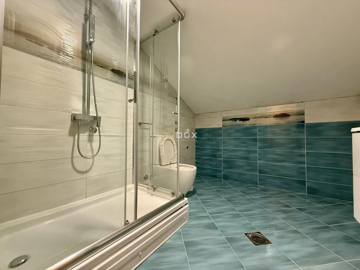 Bathroom with a shower cabin, toilet and blue tiles in the attic.