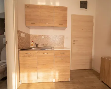 Small kitchen with wooden cabinetry and a sink. - image 8