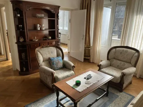 Living room with a seating arrangement, wooden display cabinet and parquet flooring. - image 3