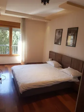 Bright bedroom with a double bed, wooden floors, and a large window. - image 3