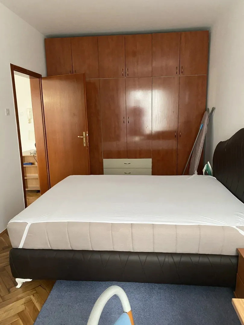 A bedroom featuring a large bed and a built-in wooden wardrobe.