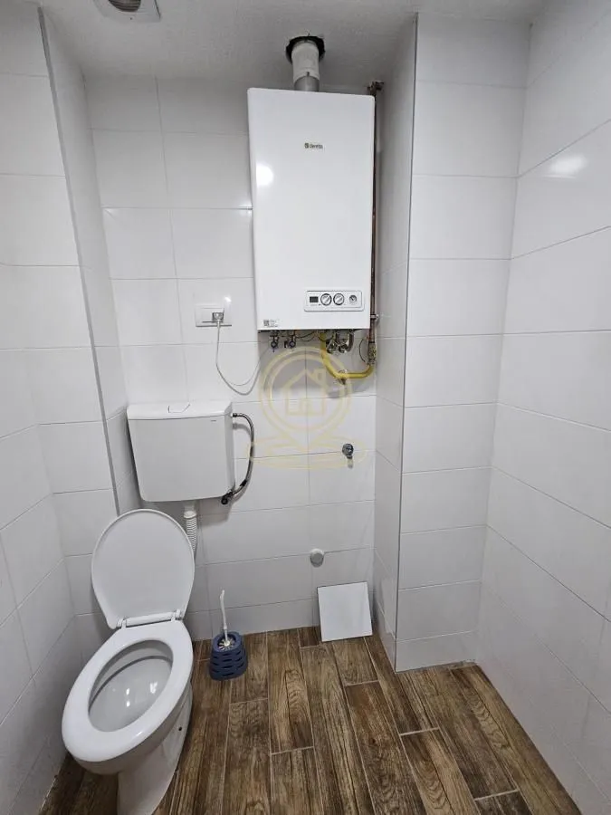 Bathroom with toilet and wall-mounted water heater.