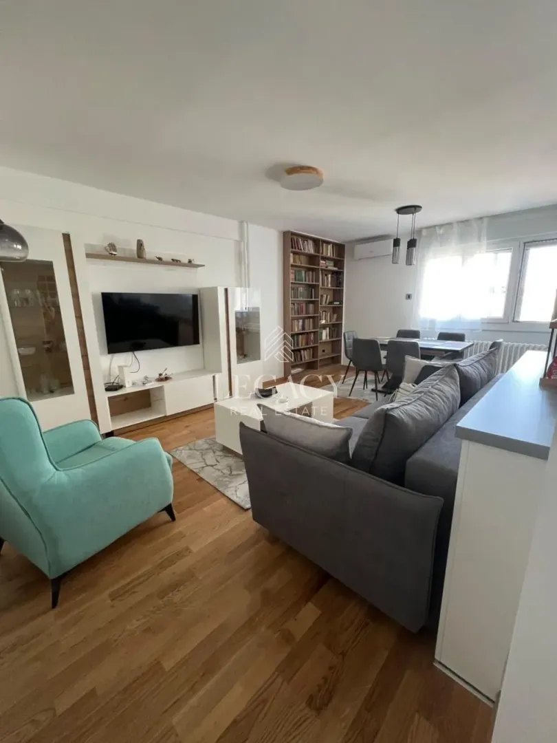 Spacious living room with a sofa set, TV, and dining area in the background.