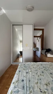 Pogled na spavaću sobu sa krevetom, ugradnim plakarom sa ogledalom i vratima koja vode u hodnik. - image 3