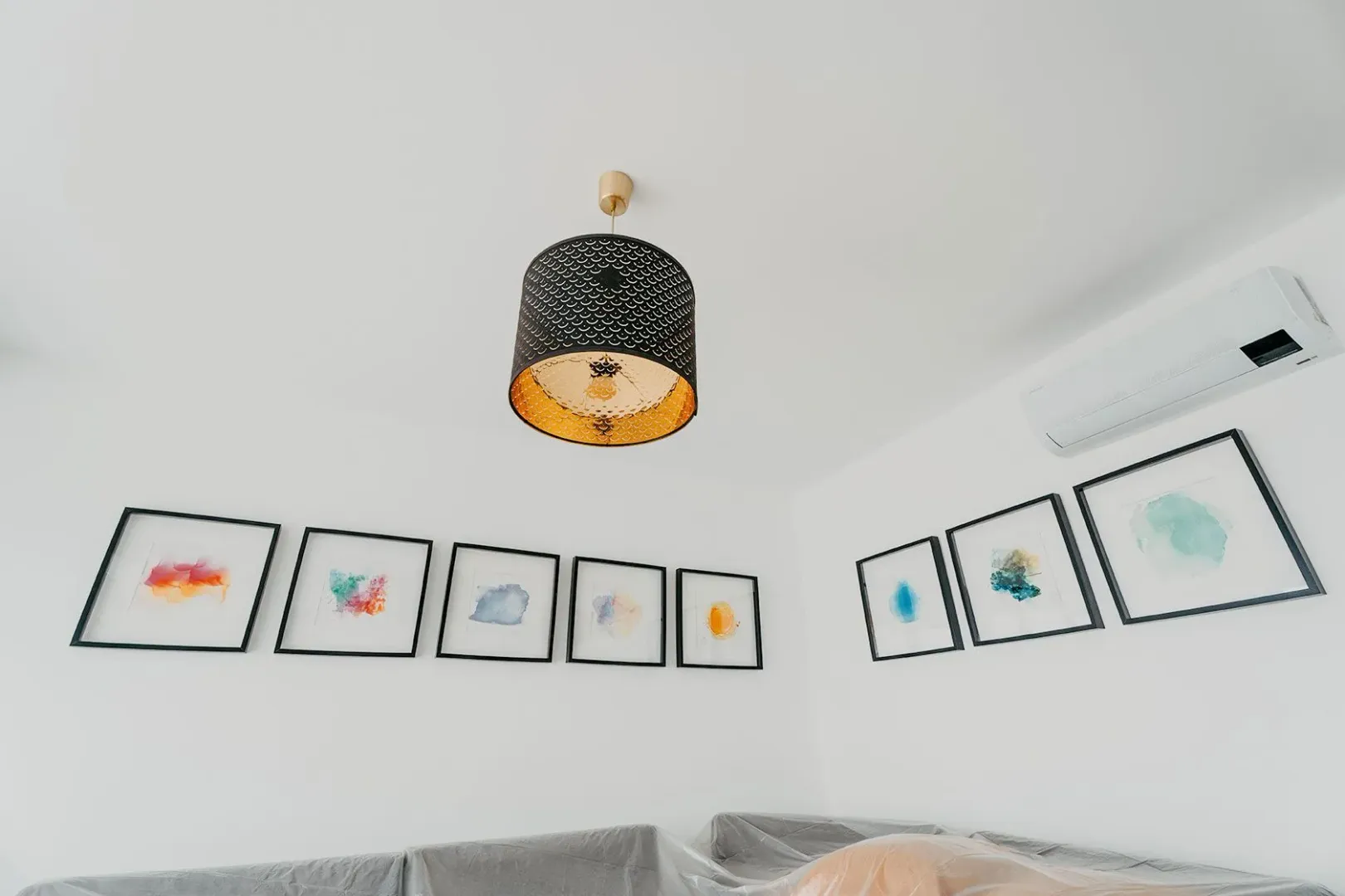 Detalj sa ugradnim klima uređajem, dekorativnim lusterom i umjetničkim slikama na zidu.
