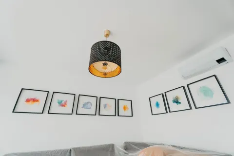 Detalj sa ugradnim klima uređajem, dekorativnim lusterom i umjetničkim slikama na zidu. - image 18
