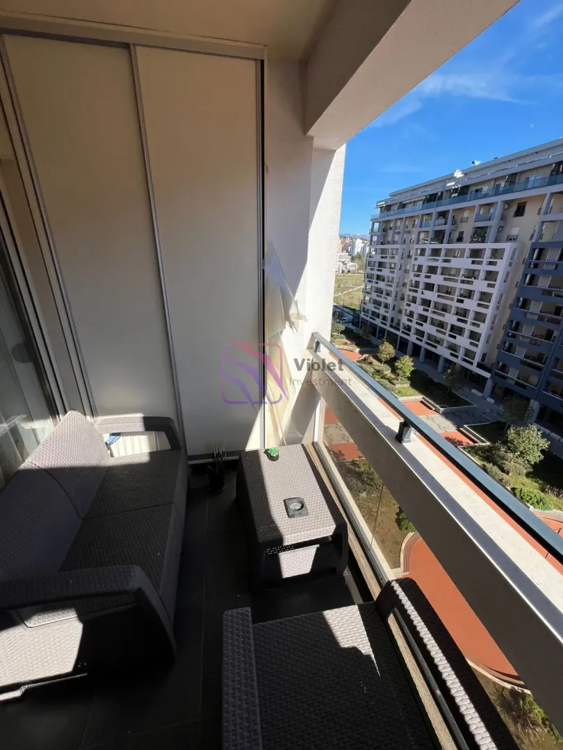 Furnished balcony with seating set and a view of surrounding buildings.
