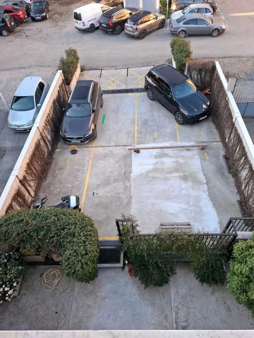 Top view of a secured parking area with marked spaces and parked cars.