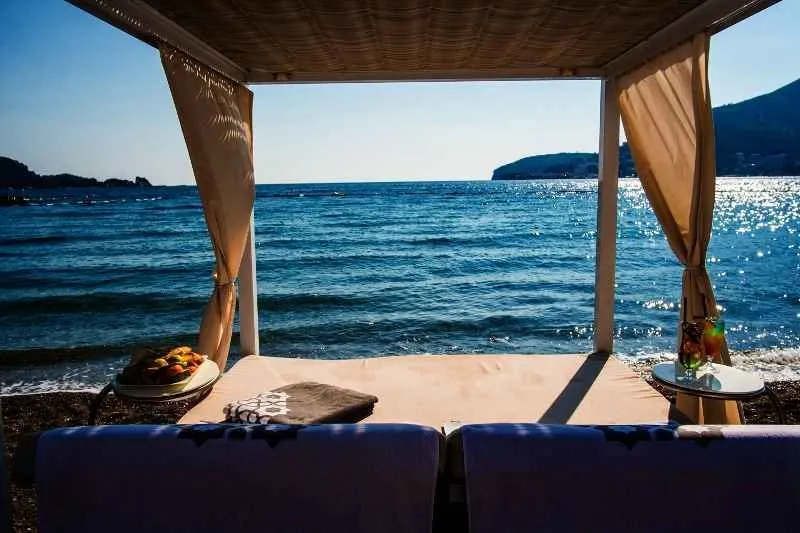 Pogled na more sa terase sa ležaljkama i baldahinom na plaži.