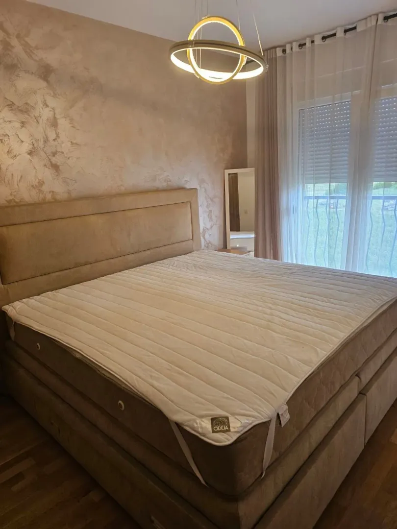 Prostrana spavaća soba sa velikim bračnim krevetom i modernim osvjetljenjem.