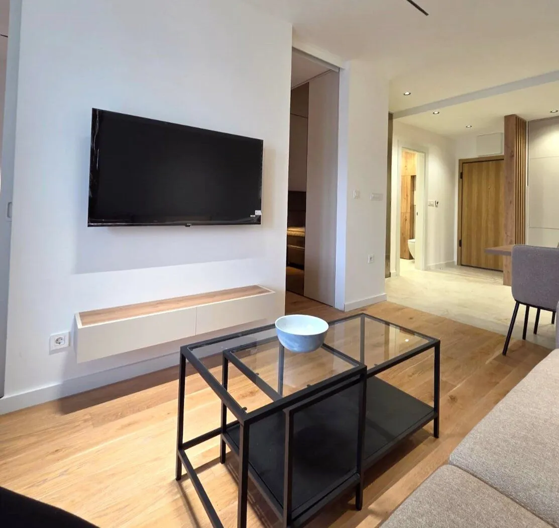 Modern living room with a sofa, coffee table, and wall-mounted TV.