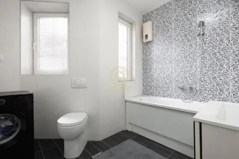 Moderno kupatilo sa kadom, toaletom i mašinom za pranje veša. - image 10