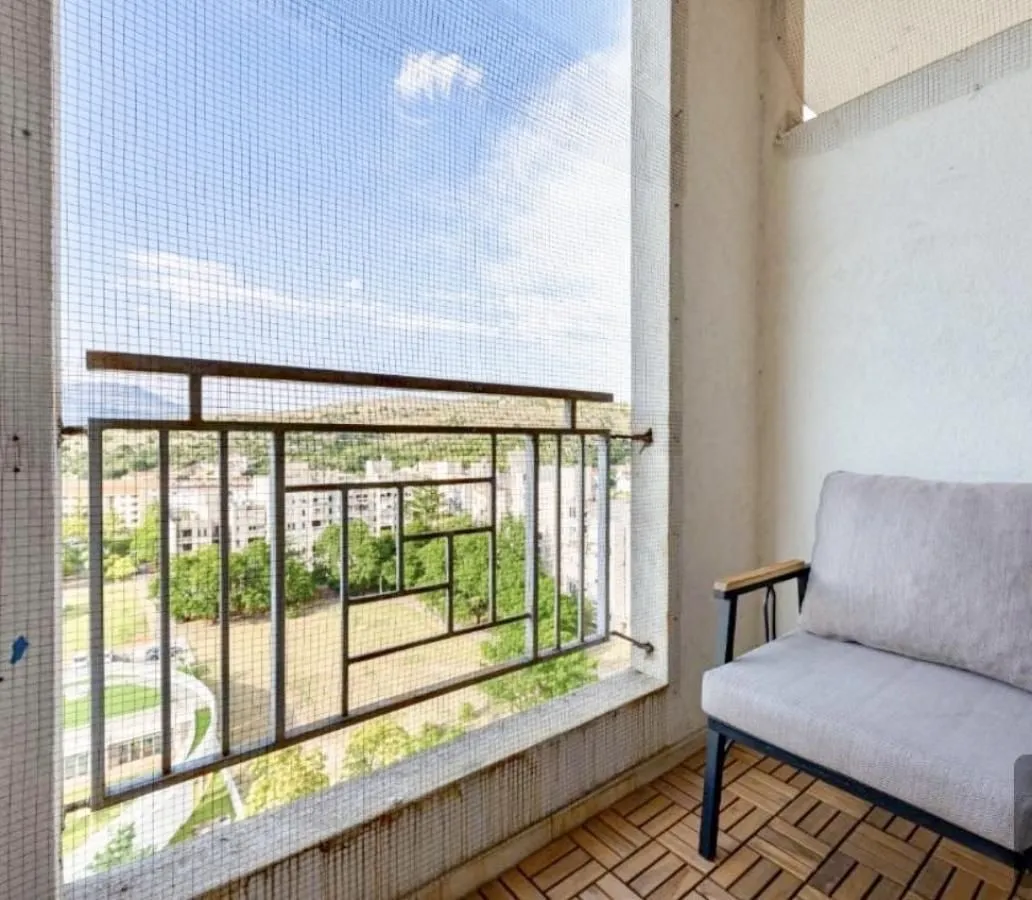 Covered balcony with an armchair and protective mesh.