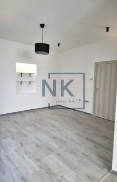 Empty room with white walls, laminate flooring, pendant light, and a door. - image 2