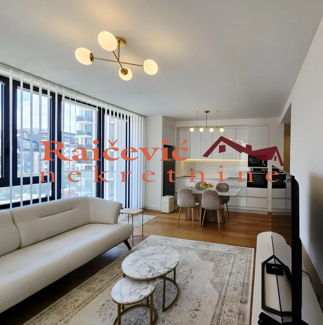 Living room connected to the dining area and kitchen, featuring large windows and a sofa.